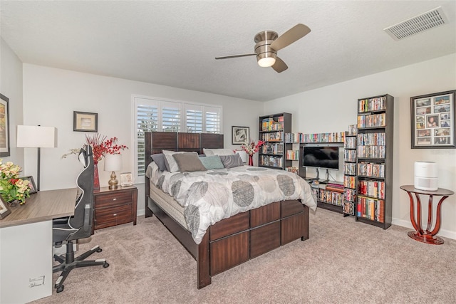 bedroom featuring a textured ceiling, light colored carpet, and ceiling fan