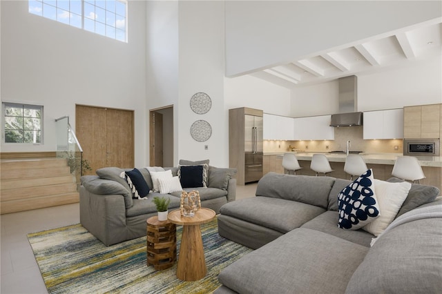 living room featuring a towering ceiling, a healthy amount of sunlight, and beamed ceiling