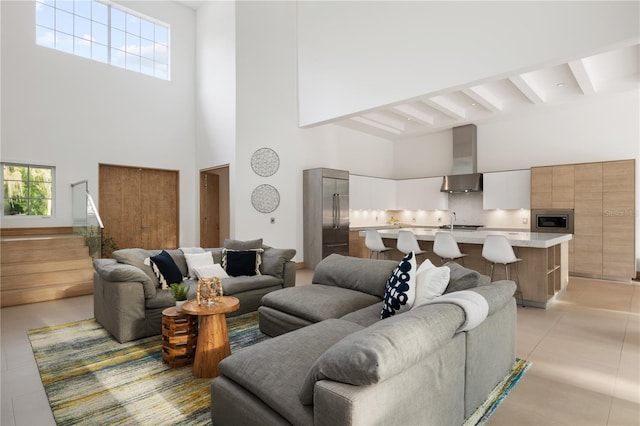 tiled living room featuring a healthy amount of sunlight, beam ceiling, sink, and a high ceiling