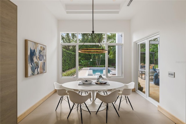 dining area featuring light tile patterned floors, plenty of natural light, and a raised ceiling