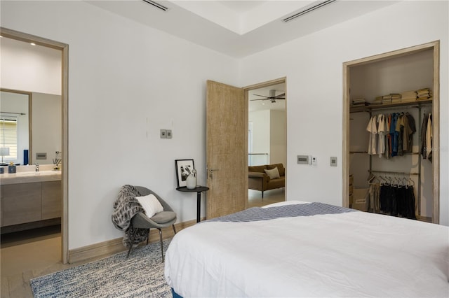 tiled bedroom featuring a spacious closet, sink, ensuite bathroom, and a closet