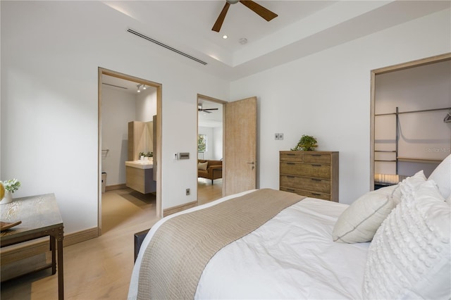 bedroom featuring connected bathroom, light carpet, and ceiling fan