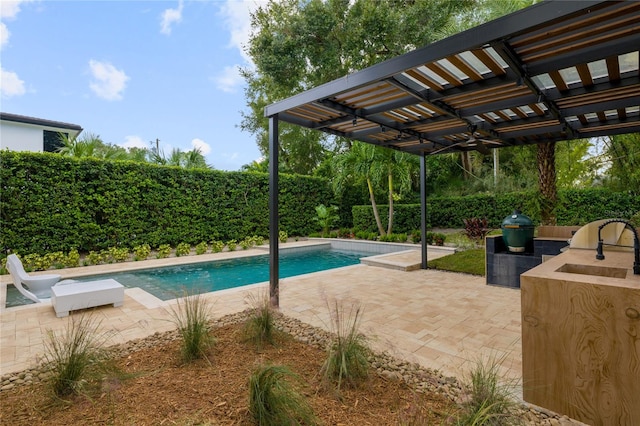 view of swimming pool with a patio, grilling area, sink, and a pergola