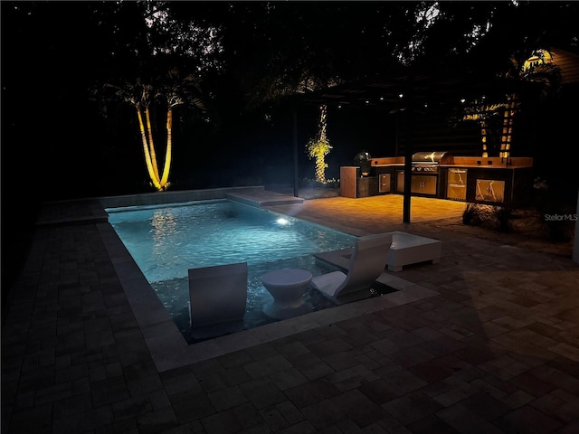 pool at night featuring grilling area, area for grilling, and a patio