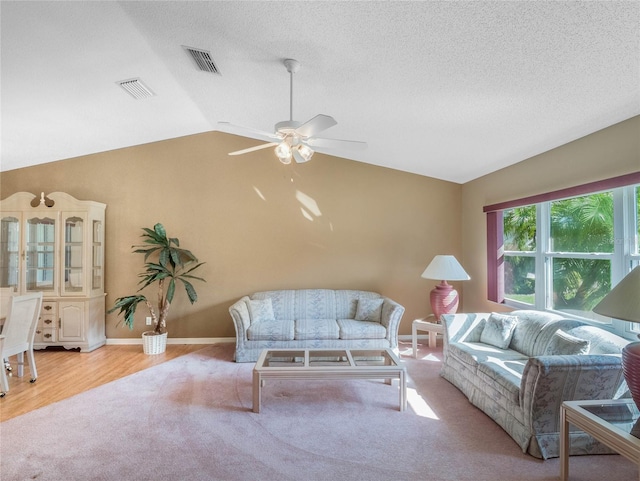 living room featuring ceiling fan, a textured ceiling, lofted ceiling, and light hardwood / wood-style floors