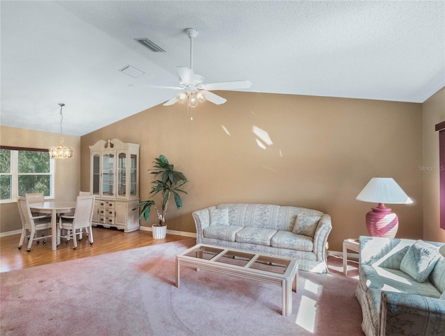 living room featuring light hardwood / wood-style floors, a textured ceiling, lofted ceiling, and ceiling fan with notable chandelier