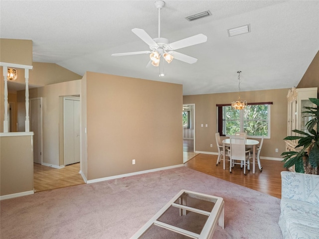 unfurnished living room featuring hardwood / wood-style floors, vaulted ceiling, a textured ceiling, and ceiling fan with notable chandelier