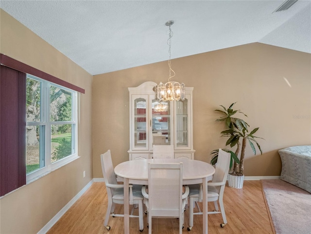 dining room with an inviting chandelier, vaulted ceiling, and light wood-type flooring