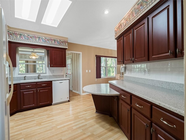 kitchen with white appliances, a healthy amount of sunlight, decorative backsplash, and light hardwood / wood-style flooring