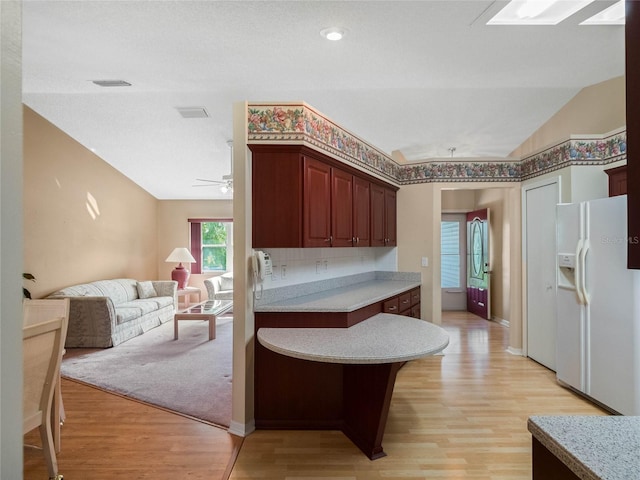 kitchen with ceiling fan, white fridge with ice dispenser, lofted ceiling, and light hardwood / wood-style flooring