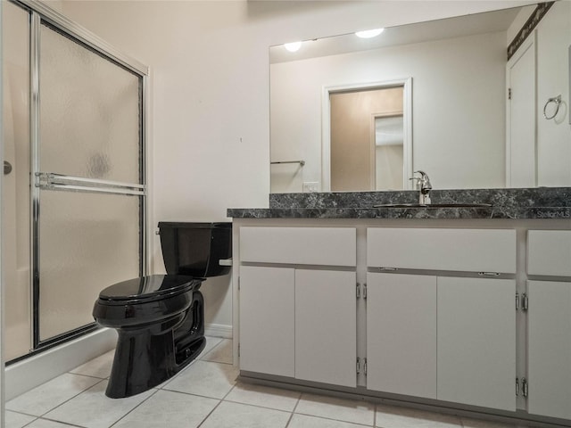 bathroom with vanity, toilet, tile patterned flooring, and a shower with door