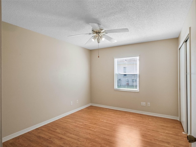 unfurnished bedroom with light hardwood / wood-style floors, a closet, a textured ceiling, and ceiling fan