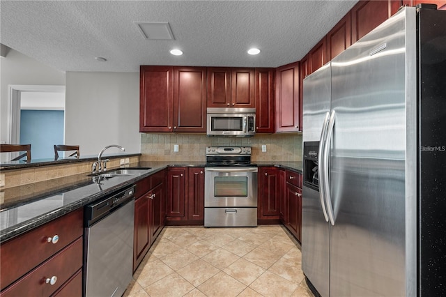 kitchen featuring decorative backsplash, dark stone counters, light tile patterned flooring, sink, and stainless steel appliances