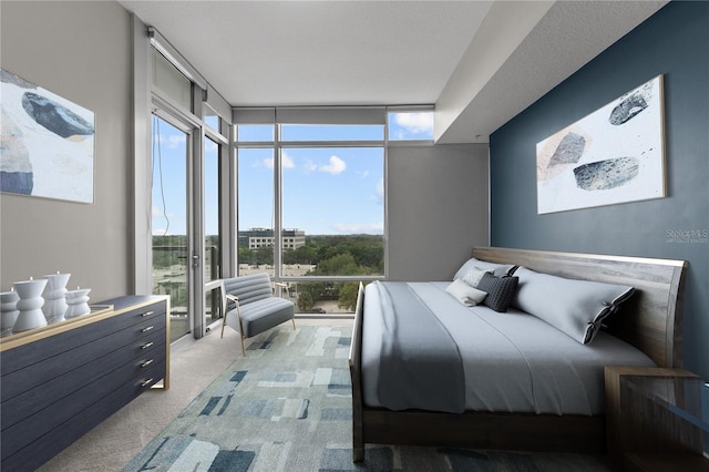 bedroom with carpet flooring, a textured ceiling, expansive windows, and multiple windows