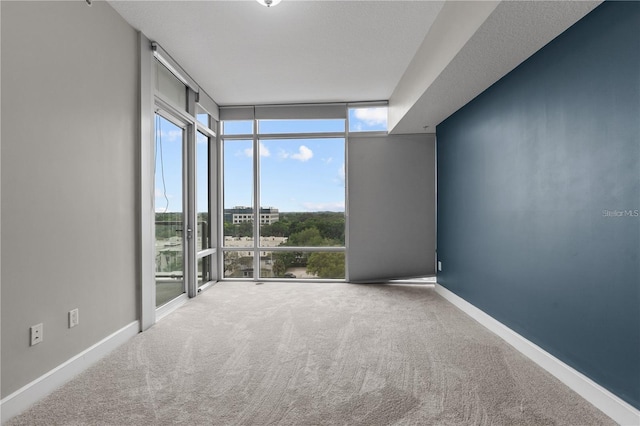 carpeted empty room with a textured ceiling and floor to ceiling windows