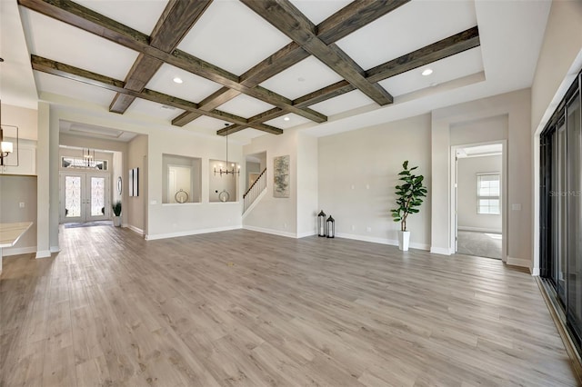 unfurnished living room featuring coffered ceiling, french doors, plenty of natural light, and light wood-type flooring