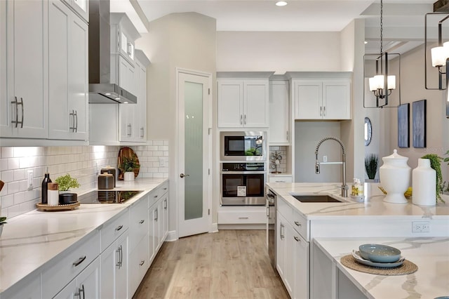 kitchen with white cabinetry, sink, wall chimney exhaust hood, built in microwave, and oven