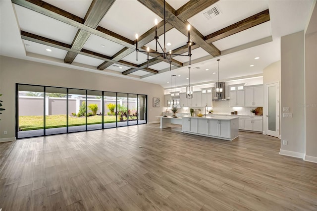 kitchen with extractor fan, decorative light fixtures, light hardwood / wood-style flooring, white cabinetry, and a large island