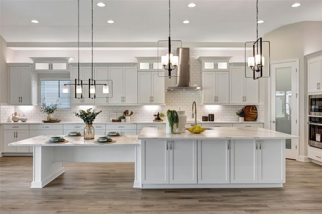 kitchen with decorative light fixtures, wall chimney exhaust hood, and a large island