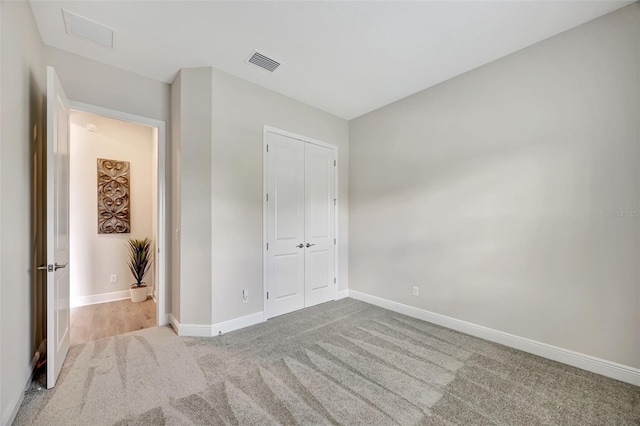 unfurnished bedroom featuring a closet and light colored carpet