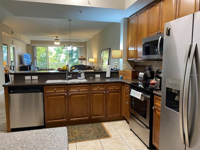 kitchen featuring stainless steel appliances, open floor plan, a sink, and a peninsula