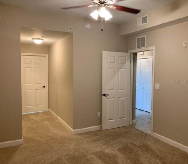 carpeted spare room with visible vents, ceiling fan, and baseboards