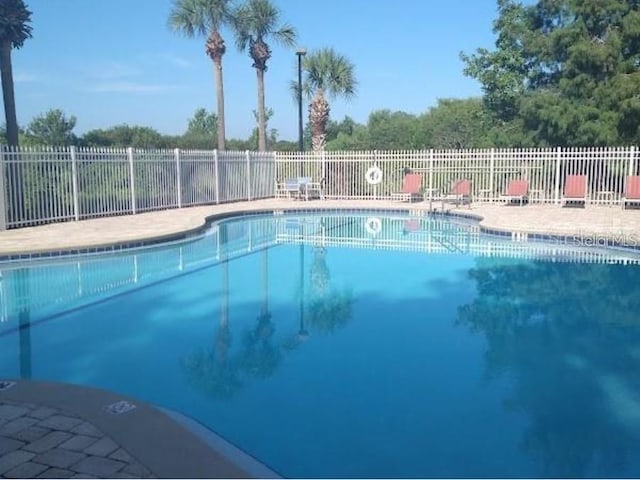 pool with a patio area and fence