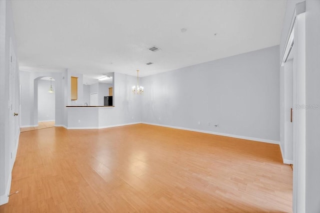 unfurnished living room with light hardwood / wood-style flooring and a notable chandelier