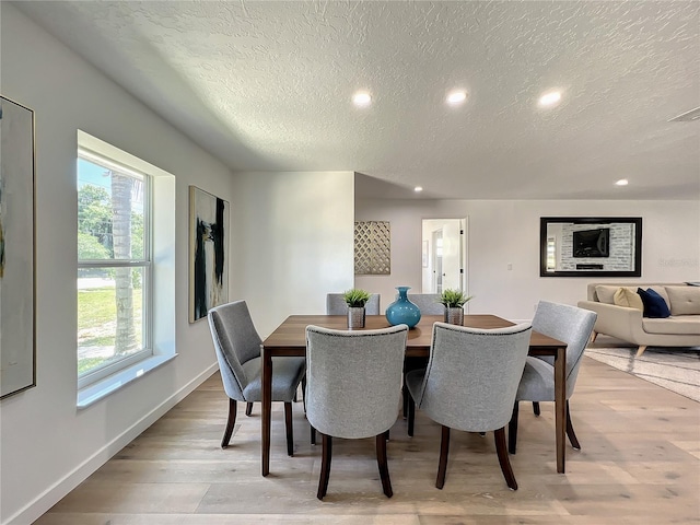 dining room with light hardwood / wood-style flooring and a textured ceiling