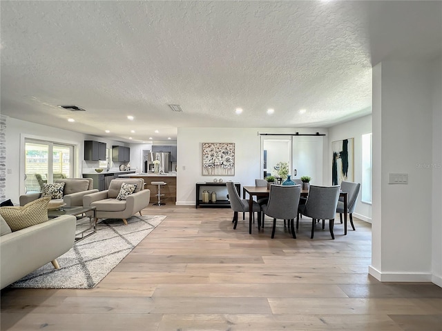 living room featuring light hardwood / wood-style floors, a textured ceiling, and a barn door