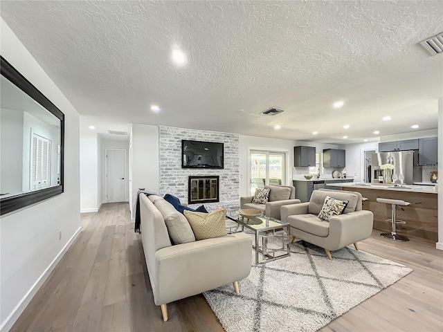 living room featuring a fireplace, a textured ceiling, and light wood-type flooring