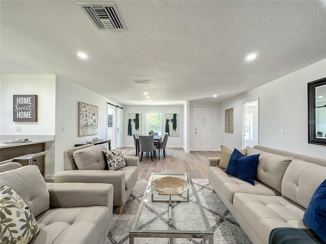 living room featuring a textured ceiling and light wood-type flooring