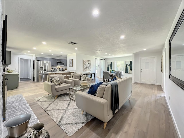 living room featuring a textured ceiling and light wood-type flooring