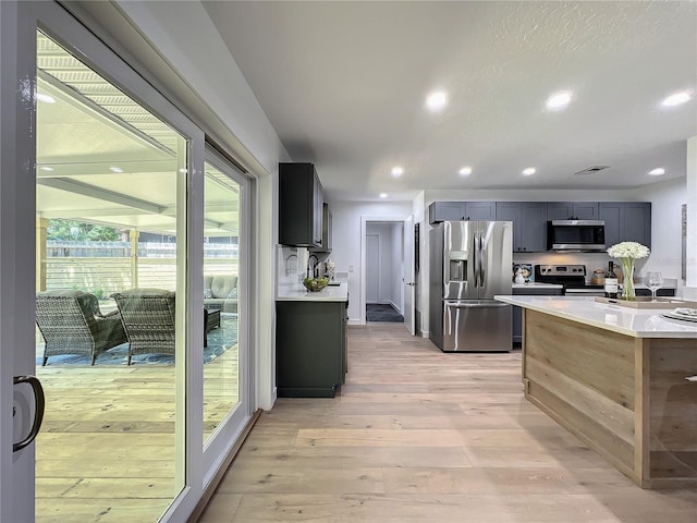 kitchen with appliances with stainless steel finishes, light hardwood / wood-style flooring, and gray cabinetry