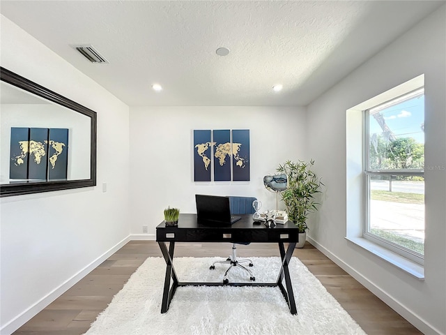 office space featuring a textured ceiling, wood-type flooring, and a wealth of natural light