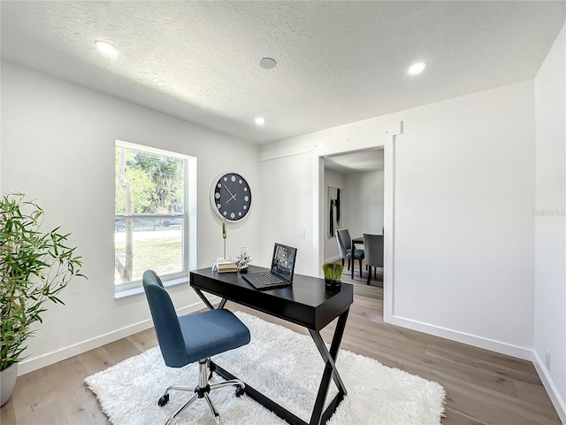 office with wood-type flooring and a textured ceiling