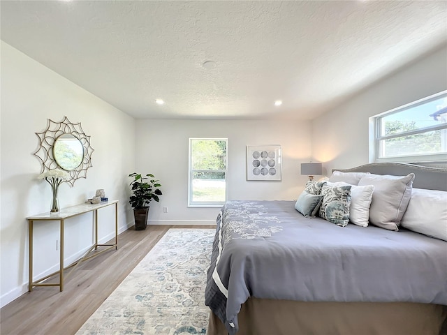 bedroom featuring a textured ceiling and light hardwood / wood-style flooring