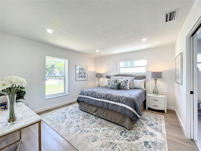 bedroom with light hardwood / wood-style flooring and a textured ceiling