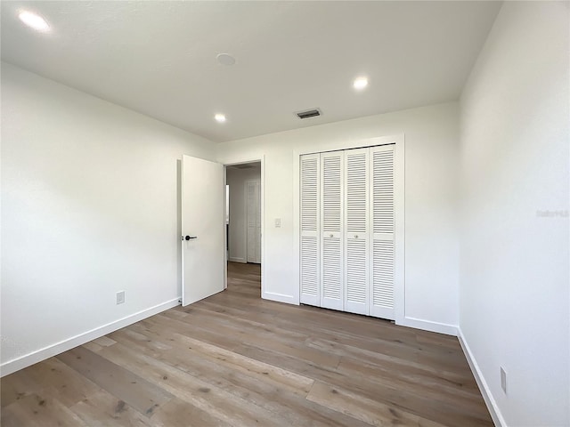 unfurnished bedroom with a closet and light hardwood / wood-style floors