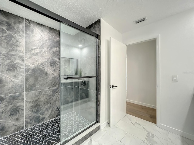 bathroom with a textured ceiling and a shower with shower door