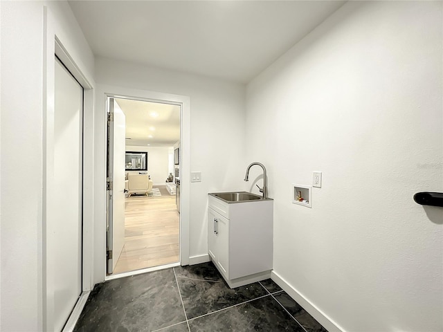 washroom with dark hardwood / wood-style flooring, sink, washer hookup, and cabinets