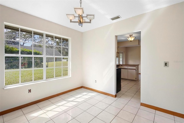 tiled empty room with a chandelier and a wealth of natural light