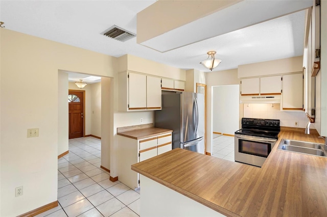 kitchen featuring kitchen peninsula, cream cabinets, stainless steel appliances, and light tile patterned floors