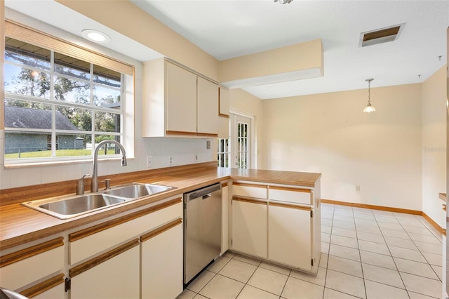 kitchen with kitchen peninsula, sink, light tile patterned flooring, pendant lighting, and stainless steel dishwasher