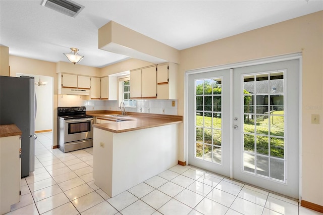 kitchen with kitchen peninsula, tasteful backsplash, light tile patterned flooring, french doors, and stainless steel appliances