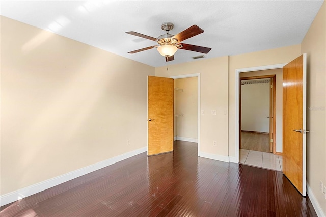 unfurnished bedroom featuring dark wood-type flooring, ceiling fan, and a closet