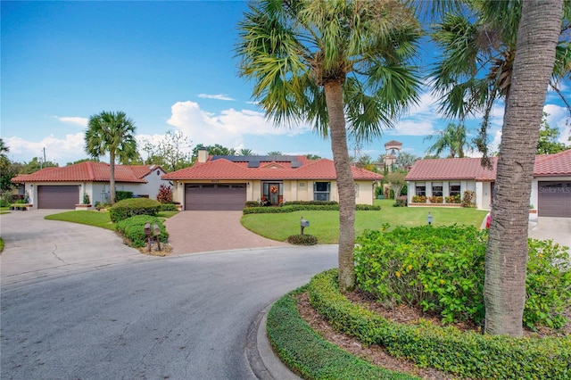 view of front of house featuring a garage, solar panels, and a front yard