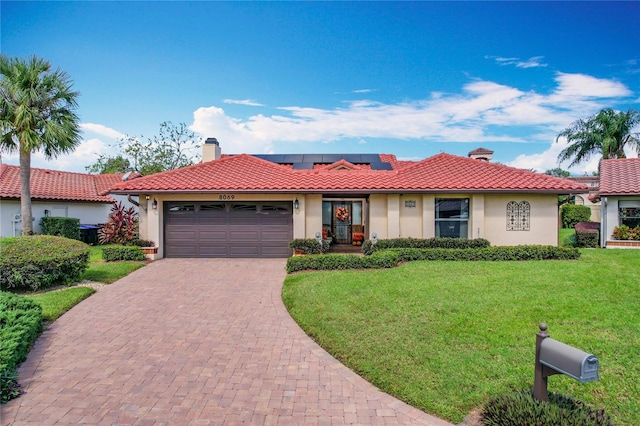 view of front of property featuring solar panels, a front lawn, and a garage