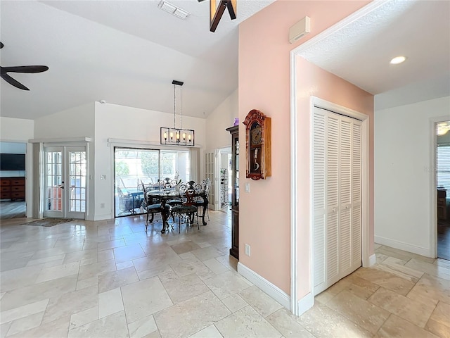 unfurnished dining area with french doors, ceiling fan with notable chandelier, and vaulted ceiling