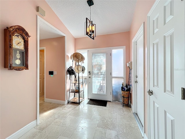 entryway with an inviting chandelier and a textured ceiling